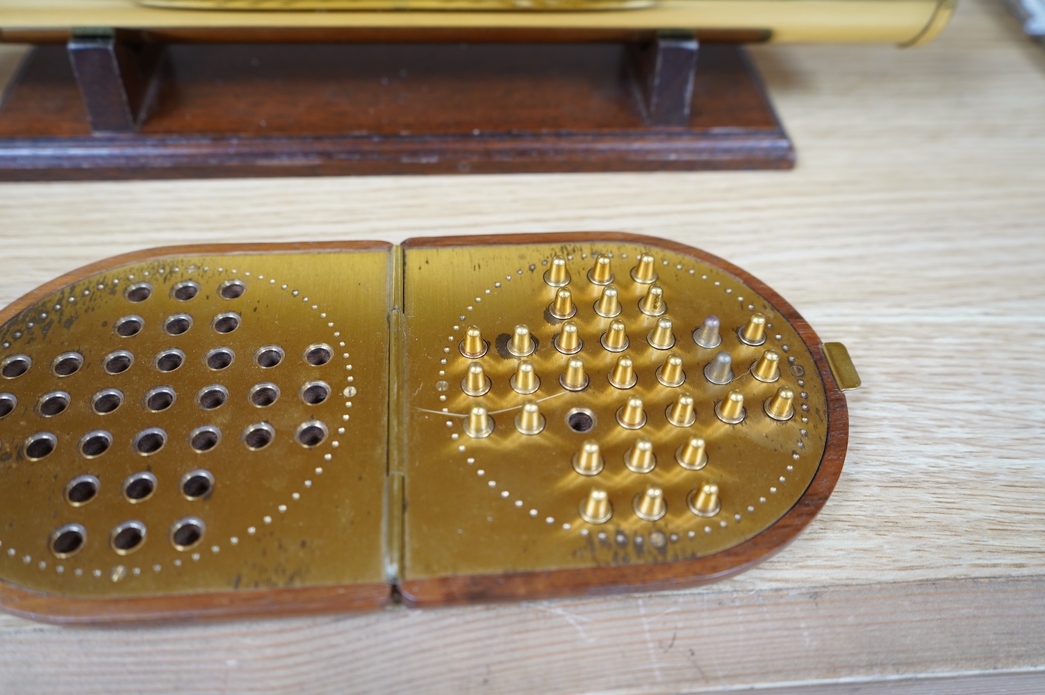 A reproduction 19th century style brass kaleidoscope by Culpeper Instruments, on a wooden stand, 33.5cm long, together with a wood cased brass solitaire set, 10.5cm diameter. Condition - fair to good.